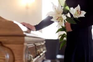 Mann mit weißen Blumen steht in der Kirche neben einem Sarg